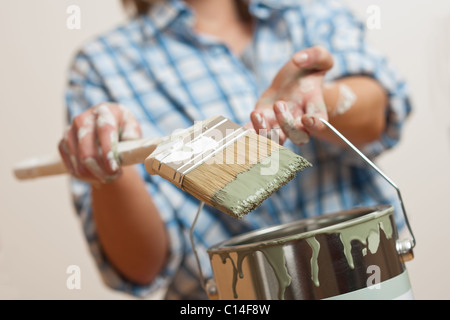 Miglioramento di casa: Donna holding spazzola di vernice e la vernice può Foto Stock