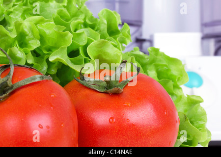 Pomodori e insalata verde foglia, cucina processore in distanza Foto Stock