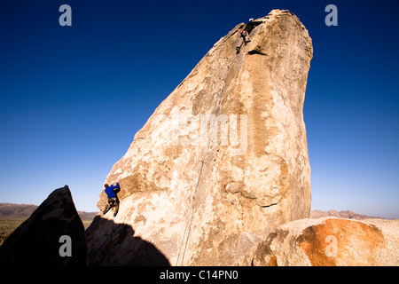 Due alpinisti maschio lavorare il loro modo fino Headstone Rock a Joshua Tree National Park, California. Foto Stock