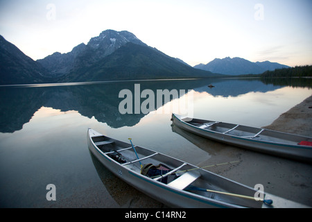 Due canoe al crepuscolo sono spiaggiata sulla riva del lago di Leigh con il Grand Tetons in distanza. Foto Stock