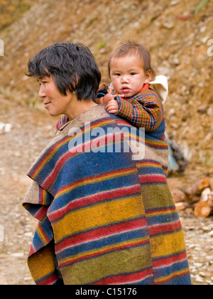 Giovane madre tibetana in Bhutan con il suo bambino sulla schiena Foto Stock