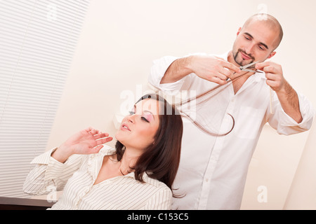 Maschio professionale parrucchiere tagliato con forbici a salon, cliente ottenendo un nuovo taglio di capelli Foto Stock