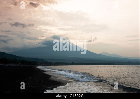 Sunrise dietro il Gunung Agung dalla Spiaggia di Amed, Bali, Indonesia. Agung è un vulcano attivo la cui ultima eruzione risale al 1963. Foto Stock