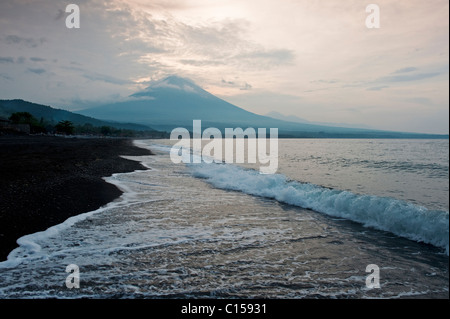 Sunrise dietro il Gunung Agung dalla Spiaggia di Amed, Bali, Indonesia. Agung è un vulcano attivo la cui ultima eruzione risale al 1963. Foto Stock