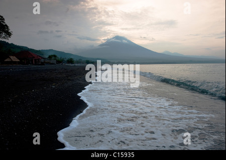 Sunrise dietro il Gunung Agung dalla Spiaggia di Amed, Bali, Indonesia. Agung è un vulcano attivo la cui ultima eruzione risale al 1963. Foto Stock