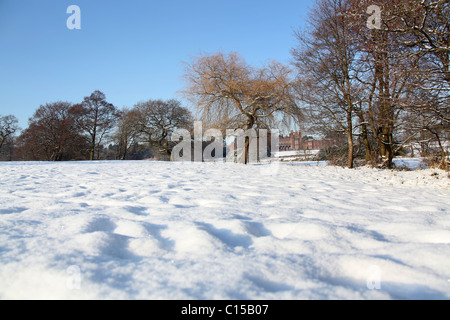 Capesthorne Hall, Inghilterra. Il pittoresco panorama invernale di una neve campo riempito con Capesthorne Hall nel lontano sullo sfondo. Foto Stock