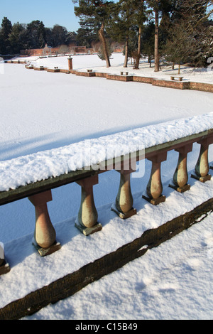 Capesthorne Hall, Inghilterra. Il pittoresco panorama invernale Capesthorne Hall giardini con il ponte balaustre in primo piano. Foto Stock