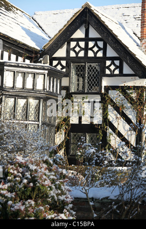 Gawsworth Old Hall, Inghilterra. Nevoso inverno vista di Gawsworth giardini e il west elevazione di Gawsworth Old Hall. Foto Stock