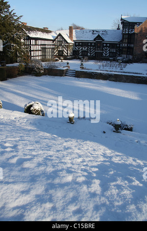 Gawsworth Old Hall, Inghilterra. Nevoso inverno vista di Gawsworth giardini e il west elevazione di Gawsworth Old Hall. Foto Stock