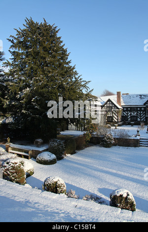 Gawsworth Old Hall, Inghilterra. Nevoso inverno vista di Gawsworth giardini e il west elevazione di Gawsworth Old Hall. Foto Stock