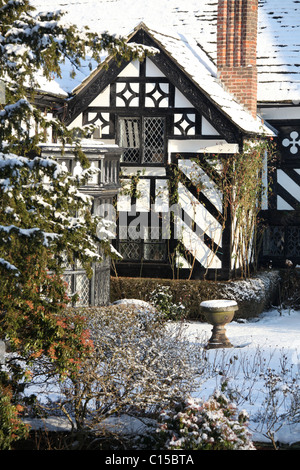 Gawsworth Old Hall, Inghilterra. Nevoso inverno vista di Gawsworth giardini e il west elevazione di Gawsworth Old Hall. Foto Stock