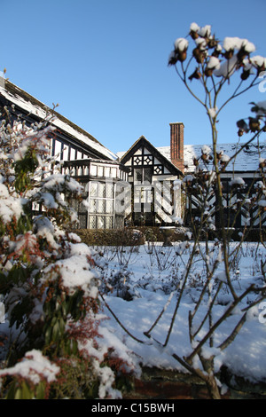 Gawsworth Old Hall, Inghilterra. Nevoso inverno vista di Gawsworth giardini e il west elevazione di Gawsworth Old Hall. Foto Stock