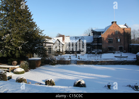 Gawsworth Old Hall, Inghilterra. Nevoso inverno vista di Gawsworth giardini e il west elevazione di Gawsworth Old Hall. Foto Stock