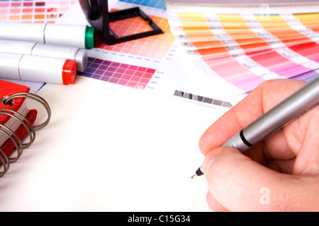 Designer circondato da design i campioni di colore e penne con carta bianca Foto Stock