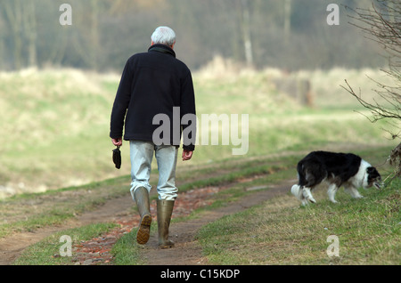 Uomo che cammina il suo hog e tenendo un poo-bag Foto Stock