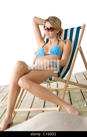 Spiaggia - Giovane donna in bikini seduto sulla sedia a sdraio relax Foto Stock