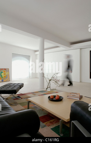 Nero sedie di Barcellona in una zona salotto con un tavolo da caffè e tappeto controllato entro un piano aperto bianco conversione di magazzino Foto Stock