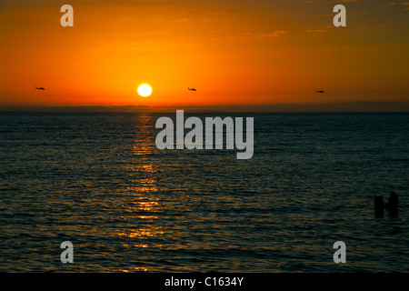 Tre elicotteri militari cavalcavia il Golfo del Messico al tramonto Foto Stock