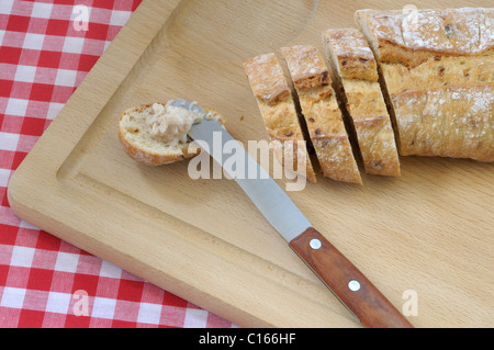 Pane, la cipolla tagliata a fette sottili di pane, coltello e scoppiettante grasso su una tavola di legno, rosso e bianco a scacchi il panno della tabella Foto Stock
