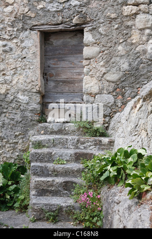 Antica casa di pietra con gradini e una porta di legno. Entrevaux, Francia Foto Stock