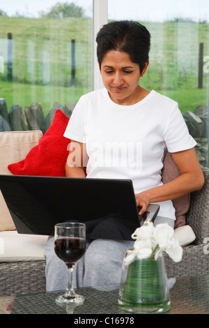 Giovani indiani donna asiatica utilizza un laptop in un elegante home Foto Stock