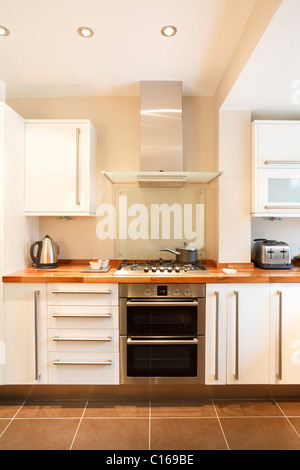 Bianca e moderna cucina con piani in legno e applicazioni in acciaio inossidabile Foto Stock