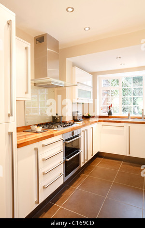 Bianca e moderna cucina con piani in legno e applicazioni in acciaio inossidabile Foto Stock