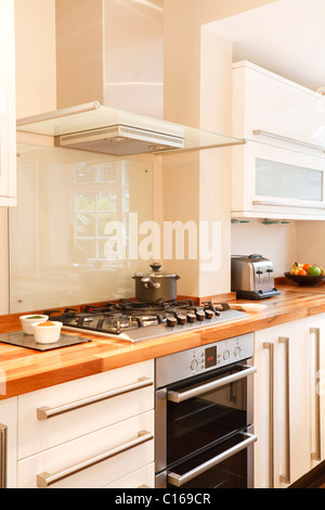 Moderna cucina bianca con acciaio inossidabile fornello, piano cottura a gas e camino estrattore Foto Stock