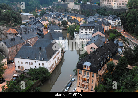 Vista dalla scogliera Bockfelsen verso il Grund quartiere con edifici residenziali sull'Alzette fiume al tramonto, Lussemburgo Foto Stock