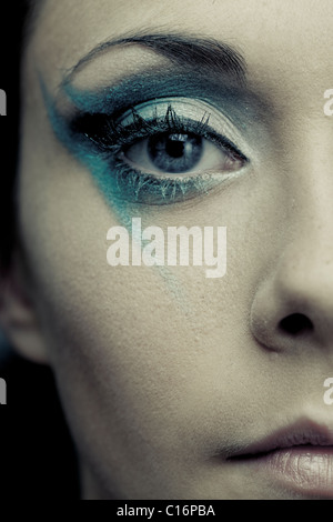 Chiudere la sezione di un viso della bambina indossa funky blue eye make up Foto Stock