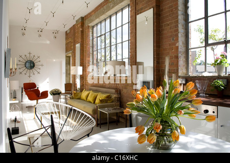 Aprire il piano cucina abitabile spazio in magazzino convertito con Crittal windows, Acapulco sedia e specchio sunburst Foto Stock