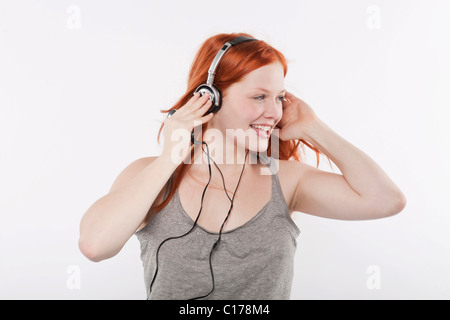 Giovane donna con lunghi capelli rossi ascoltando musica sulle cuffie Foto Stock