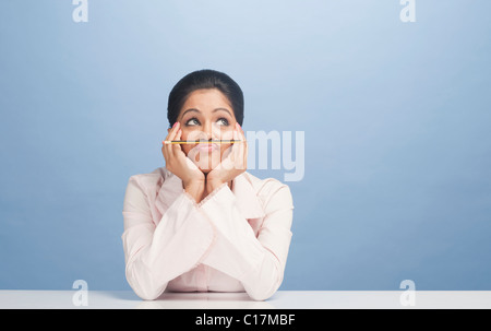 Imprenditrice matita di bilanciamento sul suo labbro Foto Stock