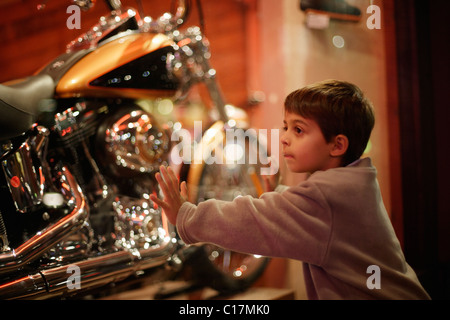 Ragazzo cerca attraverso la vetrina per motocicli Foto Stock
