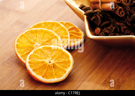 Essiccato fettine di arancia su una tavola di legno con anice stellato e bastoni cinnammon Foto Stock