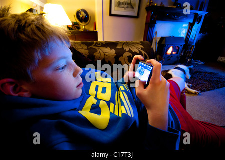 Un giovane ragazzo giocando con un I pod touch nella sua casa Foto Stock