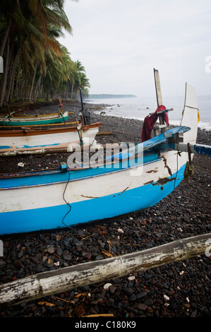 Un Balinese tradizionale barca da pesca o jukung, viene trasportata fino sulla spiaggia nel villaggio di Tembok, Bali, Indonesia. Foto Stock