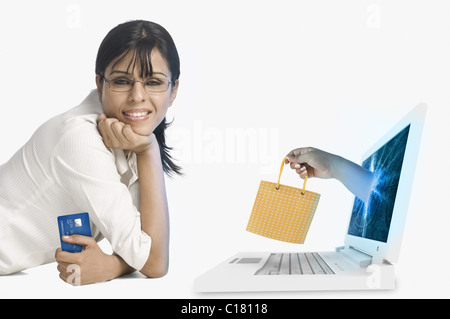 Donna sorridente con la mano che esce dal computer portatile regalo di contenimento Foto Stock