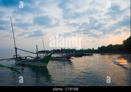 All'alba nel villaggio di Pemuteran, Bali, tradizionali barche da pesca chiamato jukung sono ancora in attesa di andare fuori per il giorno. Foto Stock