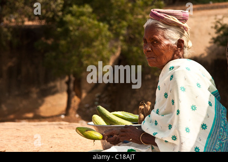 Il vecchio donna Indiana che vendono cetrioli sulla strada sotto il sole Foto Stock
