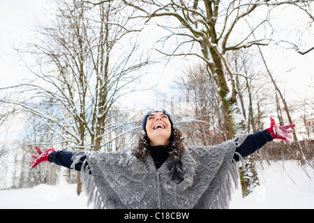 Donna in boschi innevati che abbraccia cielo Foto Stock