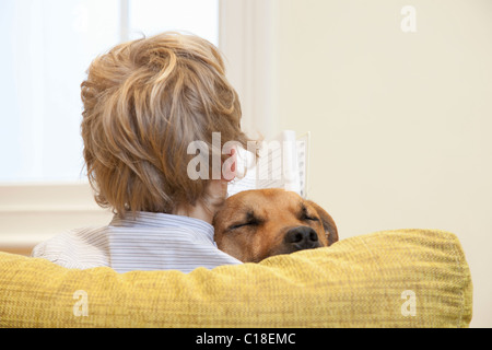 Ragazzo lettura mentre cuddling cane Foto Stock