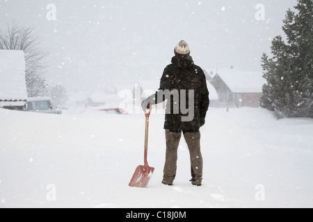 Uomo in piedi nella neve con la pala Foto Stock