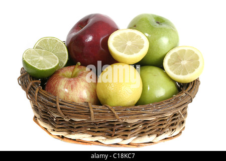 Ampia selezione di frutta colorata comprendente le mele, i limoni e limette in un cestello isolato su uno sfondo bianco. Foto Stock