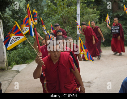 Una linea di monaci e monache stream fino alla cima di una collina azienda bandiere tibetano Foto Stock