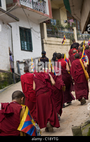 Una linea di flusso di monaci fino alla cima di una collina azienda bandiere tibetano Foto Stock