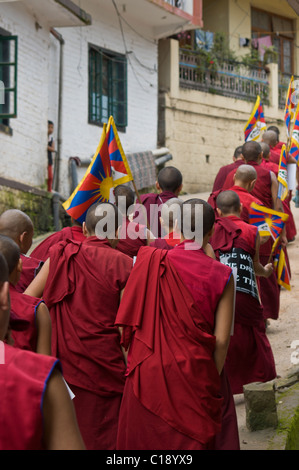 Una linea di flusso di monaci fino alla cima di una collina azienda bandiere tibetano Foto Stock