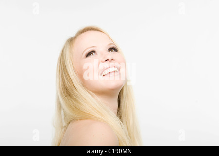 Giovane donna bionda guardando in alto, sorridente Foto Stock