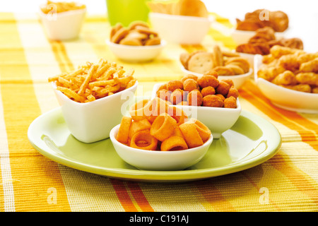 Vari snack speziato in ciotole, patatine, arachidi capriole, bastoncini di patata di arachidi tostate e anelli di patate Foto Stock