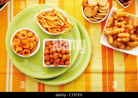 Vari snack speziato in ciotole, patatine, arachidi capriole, bastoncini di patata di arachidi tostate, pretzel bastoni e anelli di patate Foto Stock